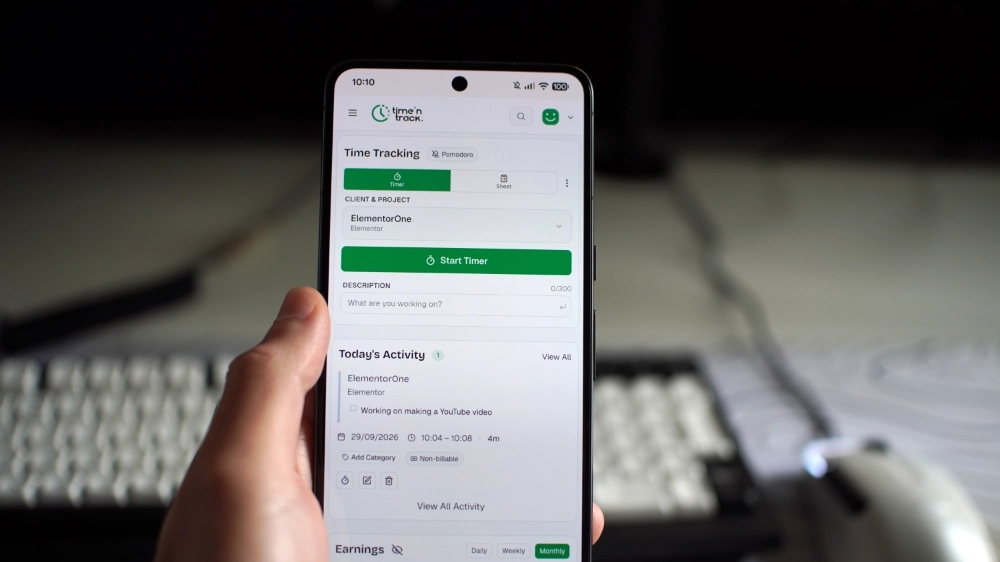 Time 'N Track app branding on a phone in hand